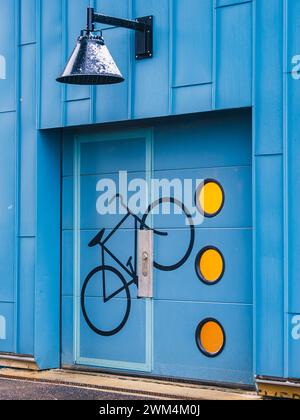 Eine auffällige blaue Tür zeigt ein bemaltes Fahrradsymbol, ergänzt durch drei hellgelbe Kreise, die eine fahrradfreundliche Einrichtung in Göteborg darstellen Stockfoto