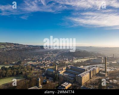 Blick aus der Vogelperspektive auf das Dorf Saltaire und die Salts Mill, die zum UNESCO-Weltkulturerbe in West Yorkshire gehören. Kaltes und frostiges Wetter mit hellem, sonnigem Himmel und anhaltendem Nebel. Stockfoto