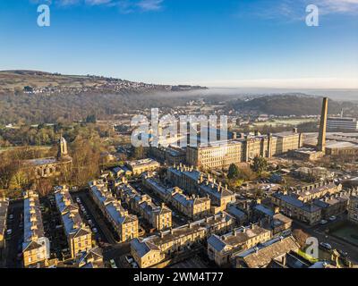 Blick aus der Vogelperspektive auf das Dorf Saltaire und die Salts Mill, die zum UNESCO-Weltkulturerbe in West Yorkshire gehören. Kaltes und frostiges Wetter mit hellem, sonnigem Himmel und anhaltendem Nebel. Stockfoto