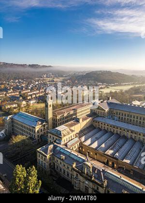 Blick aus der Vogelperspektive auf das Dorf Saltaire und die Salts Mill, die zum UNESCO-Weltkulturerbe in West Yorkshire gehören. Kaltes und frostiges Wetter mit hellem, sonnigem Himmel und anhaltendem Nebel. Stockfoto