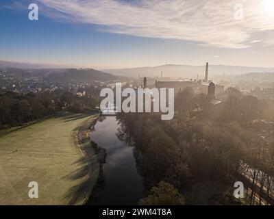 Blick aus der Vogelperspektive auf das Dorf Saltaire und die Salts Mill, die zum UNESCO-Weltkulturerbe in West Yorkshire gehören. Kaltes und frostiges Wetter mit hellem, sonnigem Himmel und anhaltendem Nebel. Stockfoto