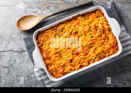 King Ranch Casserole ist ein klassisches texanisches, komfortables Essen mit Gemüse, Cheddar-Käse, Tortilla und Sahne in einer Backform auf einem Marmortisch. Ho Stockfoto