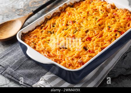 King Ranch Casserole wird mit Maistortillas gesäumt, dann mit Soße überzogen und mit Käse in einer Backform auf einem Marmortisch in Nahaufnahme garniert. Horizont Stockfoto