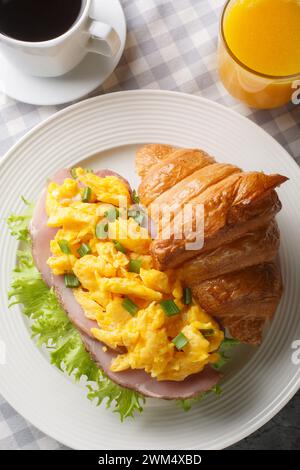 Frisches Croissant mit Omelette, Schinken, grünen Zwiebeln und Salat, serviert mit Orangensaft und Kaffee in Nahaufnahme auf einem Marmortisch. Vertikale Draufsicht von ab Stockfoto