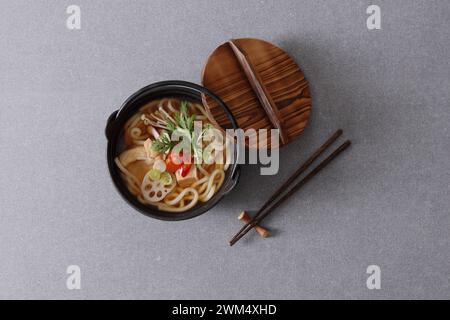Koreanische Ramen-Nudelsuppe in Schüssel mit Stäbchen auf grauem Hintergrund Stockfoto