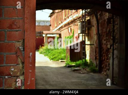 Die Textur einer alten Backsteinmauer vor dem Hintergrund des bogenförmigen Eingangs zum Innenhof Stockfoto