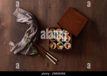 Kimbap in einer Holzkiste auf einem hölzernen Hintergrund, Blick von oben Stockfoto