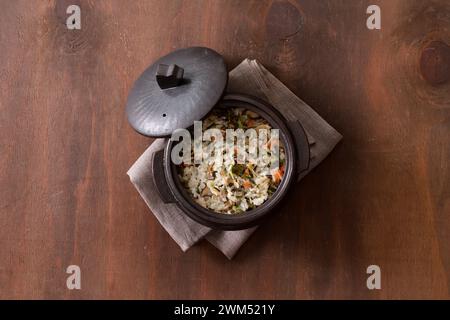 Reis mit Gemüse in einem Topf auf hölzernem Hintergrund. Draufsicht Stockfoto