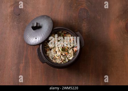 Reis mit Gemüse in einem Topf auf hölzernem Hintergrund. Draufsicht Stockfoto