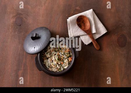 Reis mit Gemüse in einem Topf auf hölzernem Hintergrund. Draufsicht Stockfoto