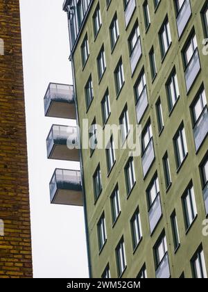 Die Fassade eines modernen Gebäudes in Göteborg ist mit einer Reihe von Balkonen zu sehen, die vor einem grauen Himmel ragen. Das Gebäude ist grün Stockfoto