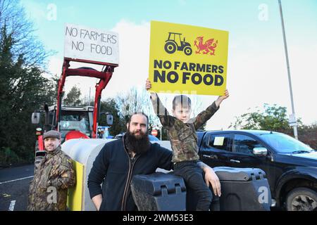 Die Bauern nehmen an einem langsamen Protest mit ihren Traktoren und Landfahrzeugen von der Penllergaer Service Station entlang der M4 in Swansea, Wales, Teil. Der Protest ruft die walisische Regierung dazu auf, ihren Plan zu überdenken, die Bauern dazu zu zwingen, 10 % ihres Ackerlandes mit Bäumen zu Pflanzen. Abgebildet ist der Landwirt Phil Andriola (Mitte) mit seinem sechsjährigen Sohn Luca. Stockfoto