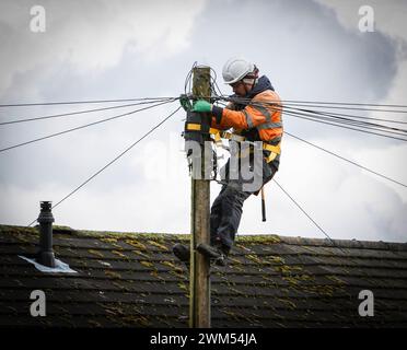 Ein Mitarbeiter von British Telecom/BT OPENREACH, Telekommunikationsingenieur hoch oben, der an einem Telegrafenmast/Strommasten arbeitet, in Hertfordshire, England, Großbritannien Stockfoto