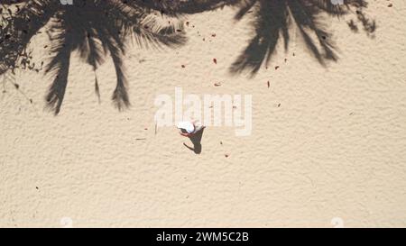 Sandstrand Palmen Hintergrund von oben nach unten. Frau in weißem Kleid geht leer perfekte Küste, ideale Küste, entspannen, genießen Sie Outdoor Lifestyle Reisen im Sommerurlaub. Drohnenaufnahme. Stockfoto