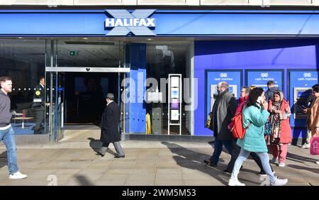 Am 24. Februar 2024 laufen die Menschen an der Niederlassung der Halifax Bank in Piccadilly, Manchester, UK, vorbei. Am 22. Februar überraschte die Halifax Bank den Markt mit einer Senkung der Hypothekenzinsen, nachdem die meisten Kreditgeber die Hypothekenpreise erhöht hatten. Stockfoto