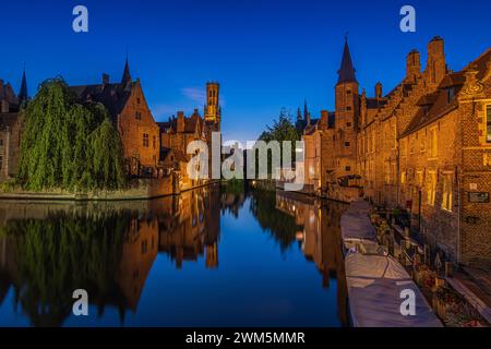 Brügge am Abend zur blauen Stunde. Der Rosenkranzquay-Kanal im Zentrum der Hansestadt. Beleuchtete Gebäude und Glockenturm der Altstadt. Stockfoto