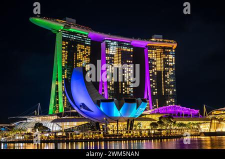 Singapur, 24. Januar 2024: Das Marina Bay Sands Hotel in Singapur ist nachts hell und reflektiert im Wasser. ArtScience Museum und Stockfoto