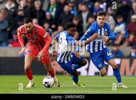 Evertons Dwight McNeil (links) und Brighton und Hove Albions Tariq Lamptey (Mitte) kämpfen um den Ball, als Brighton und Hove Albions Facundo Buonanotte (rechts) während des Premier League-Spiels im American Express Stadium in Brighton zuschauen. Bilddatum: Samstag, 24. Februar 2024. Stockfoto