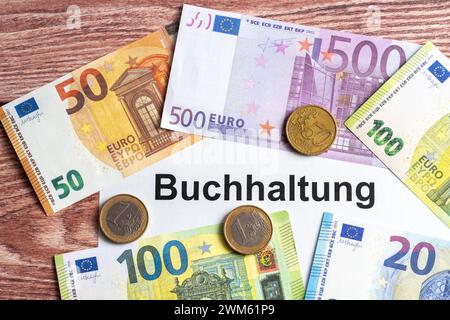 Augsburg, Bayern, Deutschland - 24. Februar 2024: Euro-Banknoten mit einem Dokument mit der Aufschrift: Accounting *** Euro Geldscheine mit einem Dokument mit Aufschrift: Buchhaltung Stockfoto