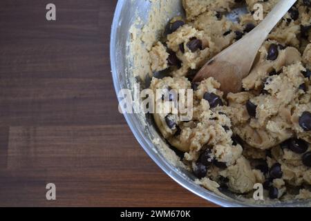 Schokoladen-Chip-Keksenteig in einer Metallschale mit Holzlöffel Stockfoto