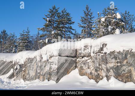 Mauer eines alten Marmorbruchs unter dem Schnee an einem sonnigen Januartag. Ruskeala Mountain Park. Karelien, Russland Stockfoto