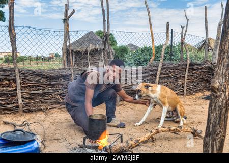 Ein afrikanischer Dorfmensch und sein Hund kochen im Freien, in Südafrika Stockfoto