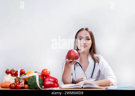 Lächelnde Ernährungswissenschaftlerin in ihrem Büro zeigt sie gesundes Gemüse und Obst, Gesundheit und Diät Konzept Stockfoto