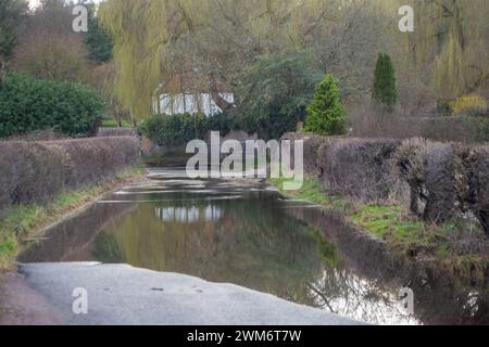 Chalfont St Giles, Großbritannien. Februar 2024. Eine überflutete Straße. Überflutungen sind im Dorf Chalfont St Giles in Buckinghamshire zu finden. Obwohl die Felder und das Stadtzentrum anfällig für Hochwasser sind, glauben einige Anwohner laut sozialen Medien, dass das anhaltende Ausmaß der Überschwemmung auf den HS2-Tunnel in den Kreideflächen für die High Speed Rail Chiltern-Tunnel zurückzuführen sein könnte, der Wasser verdrängt. Quelle: Maureen McLean/Alamy Live News Stockfoto