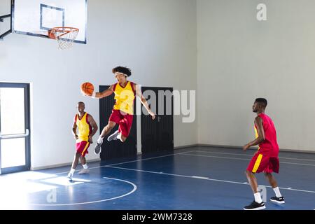 Junger afroamerikanischer Mann springt für einen Basketballschuss in einem Fitnessstudio Stockfoto