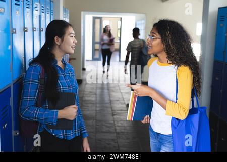 Ein asiatisches Teenager-Mädchen plaudert mit einer birassischen Frau in der High School Stockfoto