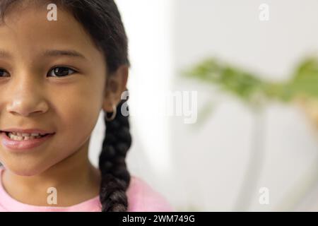 Ein birassisches Mädchen lächelt sanft in einem hellen Raum mit Kopierraum Stockfoto