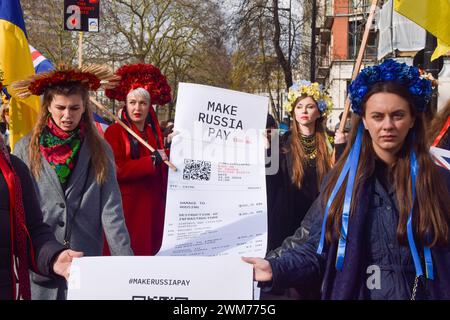 London, Großbritannien. Februar 2024. Die Demonstranten halten eine riesige Rechnung für Russland, während Tausende von Menschen in Zentral-London in Solidarität mit der Ukraine am zweiten Jahrestag des Angriffs Russlands marschieren. Quelle: Vuk Valcic/Alamy Live News Stockfoto