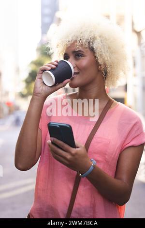 Eine junge Frau, die eine Rasse hat, genießt einen Kaffee im Freien in der Stadt Stockfoto