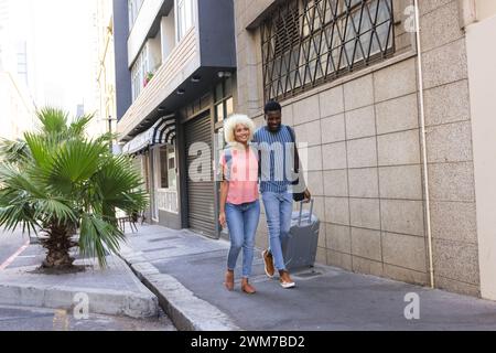 Diverse birassische Paare, die im Urlaub in einer Stadtstraße spazieren gehen Stockfoto