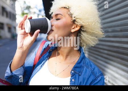 Eine junge Frau, die eine Rasse hat, genießt einen Kaffee im Freien in der Stadt Stockfoto