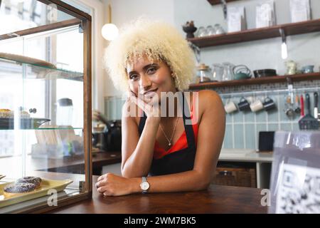 Die junge Barista, weibliche Biracial-Café-Besitzerin, lächelt in einem gemütlichen Café Stockfoto