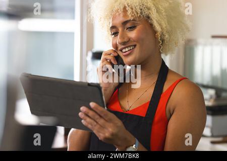 Junge Biracial weibliche Café-Besitzerin Barista multitasken in einem modernen Büro Stockfoto