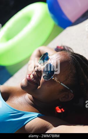 Die junge Frau genießt die Sonne am Pool und verfügt über einen Kopierraum Stockfoto