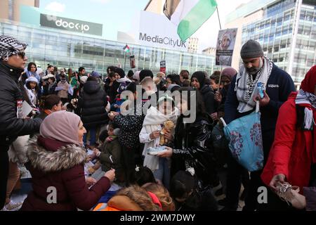 Salford, Großbritannien. Februar 2024. Hunderte von Familien versammeln sich mit ihren Kindern, um gegen die BBC und ihre "voreingenommene" Berichterstattung über die Bombardierung Palästinas zu protestieren. Die Demonstranten forderten ein freies Palästina und einen Waffenstillstand. Die Kinder hielten Drachen in Solidarität mit den Kindern im Gazastreifen auf, die das guiness-Buch der Rekorde für die meisten gleichzeitig geflogenen Drachen halten. Die Kinder verbanden auch Puppen und stellten Plakate zusammen, die einen Haufen Kinderschuhe hinterließen, um die Kinder zu repräsentieren, die in Gaza getötet wurden. Media City, Salford, Großbritannien. Quelle: Barbara Cook/Alamy Live News Stockfoto