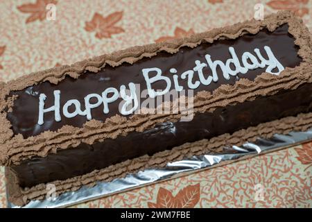 Feierliche Freude. Schokoladenkuchen mit Happy Birthday weißen Buchstaben. Herbstmotiv, Blatttabelle. Stockfoto