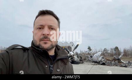 Kiew, Ukraine. Februar 2024. Der ukrainische Präsident Wolodymyr Zelenskyj hält am 2. Jahrestag der Invasion auf dem Flughafen Hostomel am 24. Februar 2024 in Kiew, Ukraine, Videokommentare vor Flugzeugen, die bei der russischen Invasion zerstört wurden. Quelle: Pool Photo/Ukrainische Präsidentenpresse/Alamy Live News Stockfoto