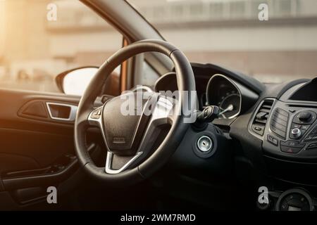 Economy Car Interieur bei Sonnenuntergang. Lenkrad und Mittelkonsole mit Tasten. Stockfoto