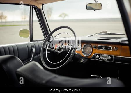 Innenraum für Oldtimer mit schwarzem Leder und Türverkleidung. Innenraum eines alten Autos aus den 1960er Jahren mit Holzfrontverkleidung. Stockfoto