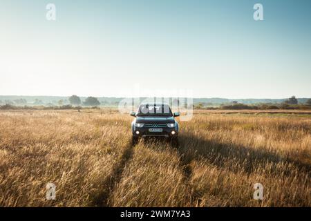 Schwarzer Mitsubishi SUV-Pickup-Truck auf einer Wiese. Morgenlicht um 6:00 Uhr, symmetrischer Blick von vorne Stockfoto