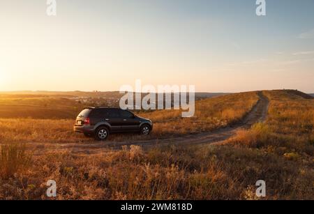 Schwarzer KIA Sorento SUV oben auf dem Hügel. Warmes Licht bei Sonnenuntergang Stockfoto