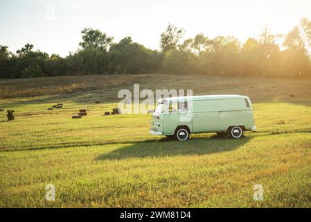 Grüner klassischer Volkswagen Transporter Transporter auf unbefestigter Landstraße, Seitenansicht. Stockfoto