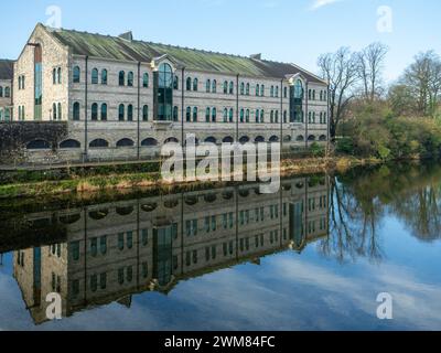 Büros mit ebenerdigen Parkplätzen im traditionellen Stil, die sich an einem hellen, sonnigen Wintertag mit Bäumen im Fluss Kent spiegeln Stockfoto