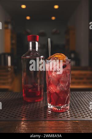 Roter Cocktail mit Orangenscheibe, serviert mit Trinkstroh Stockfoto