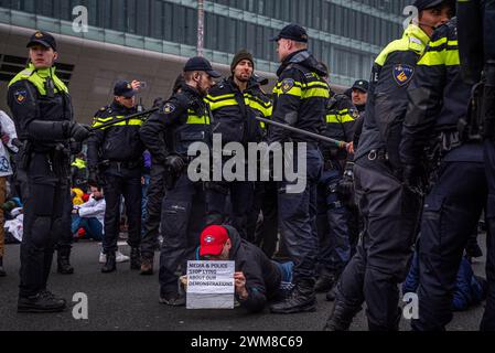 Amsterdam, Nordholland, Niederlande. Februar 2024. Die niederländische Polizei steht über einen verhafteten Aktivisten. Am 24. Februar 2024 blockierten Aktivisten die A10, eine Hauptstraße in Amsterdam, Niederlande. Ihre Forderung lautete, dass die ING Bank ihre Investitionen in die fossile Brennstoffindustrie einstellen sollte. (Kreditbild: © James Petermeier/ZUMA Press Wire) NUR REDAKTIONELLE VERWENDUNG! Nicht für kommerzielle ZWECKE! Stockfoto