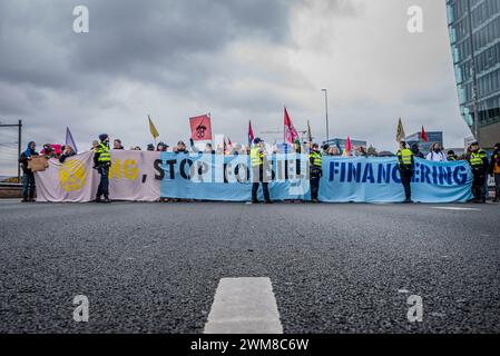 Amsterdam, Nordholland, Niederlande. Februar 2024. Von der niederländischen Polizei blockiert, halten Aktivisten Banner, während sie die Autobahn A10 blockieren. Am 24. Februar 2024 blockierten Aktivisten die A10, eine Hauptstraße in Amsterdam, Niederlande. Ihre Forderung lautete, dass die ING Bank ihre Investitionen in die fossile Brennstoffindustrie einstellen sollte. (Kreditbild: © James Petermeier/ZUMA Press Wire) NUR REDAKTIONELLE VERWENDUNG! Nicht für kommerzielle ZWECKE! Stockfoto